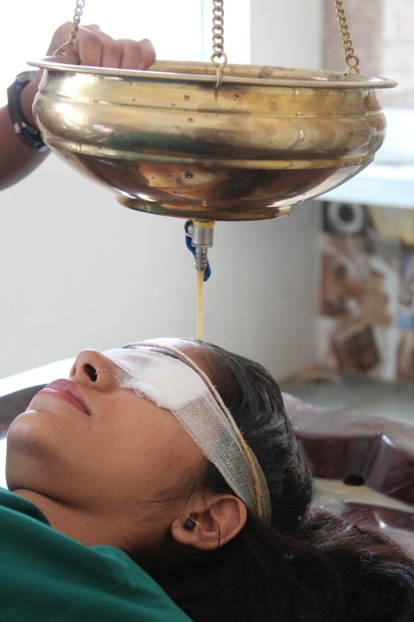 A patient receiving Shirodhara in the Panchakarma theatre